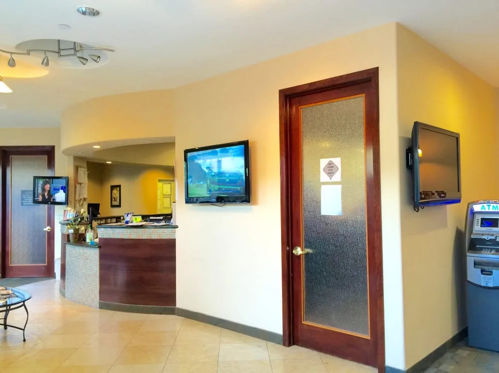 Reception area with a front desk, a wall-mounted TV and a frosted glass door