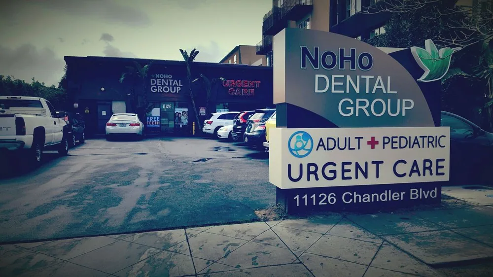 Roadside sign for NoHo Dental Group at 11126 Chandler Blvd in front of a parking area