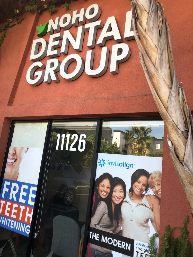 Storefront sign reading NoHo Dental Group beside windows with promotional posters