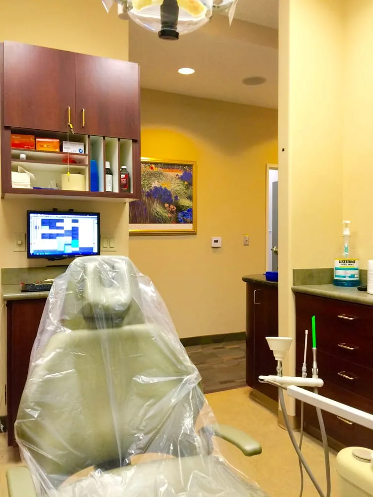 Dental chair in a treatment room with a computer monitor and wood cabinets