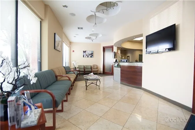 Waiting area with upholstered seating, a reception desk and a wall-mounted TV